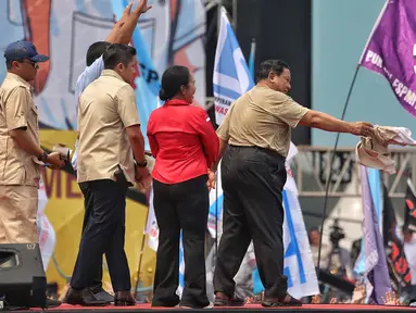 Presiden Prabowo Subianto (kanan-baju coklat) memberikan kemeja yang dikenakannya kepada peserta aksi perayaan Hari Buruh Internasional 2025 di kawasan Monumen Nasional (Monas), Jakarta, Kamis (1/5/2025). (Liputan6.com/Angga Yuniar)