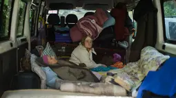 Dua perempuan duduk di dalam sebuah van saat mereka dievakuasi di Bakhmut, Ukraina timur, Selasa (24/5/2022). Kota Bakhmut telah mengalami peningkatan serangan artileri, terutama selama seminggu terakhir, ketika pasukan Rusia mencoba untuk terus maju mengepung kota Sieverodonetsk di timur laut. (AP Photo/Francisco Seco)
