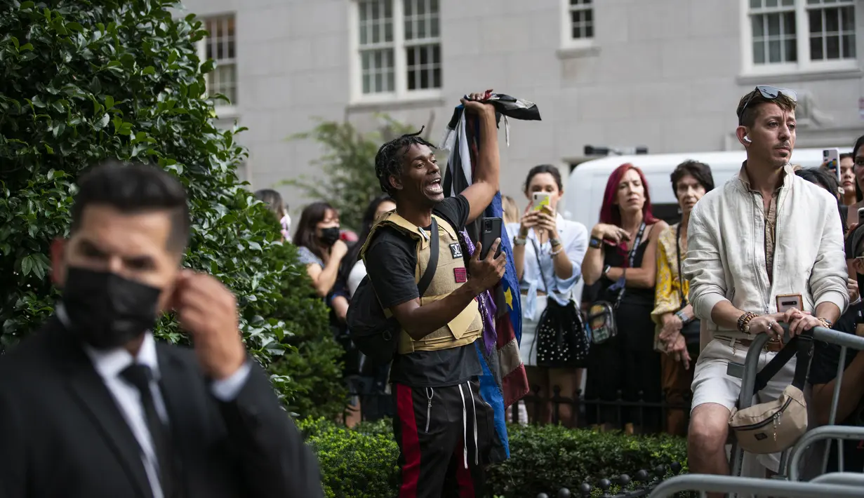 Seorang pengunjuk rasa meneriakkan slogan-slogan melawan polisi di sebelah penggemar yang menunggu kedatangan selebriti selama protes "Defund the Police" di luar Metropolitan Museum of Art selama MET Gala di New York (13/9/2021). (AFP/Eduardo Munoz)