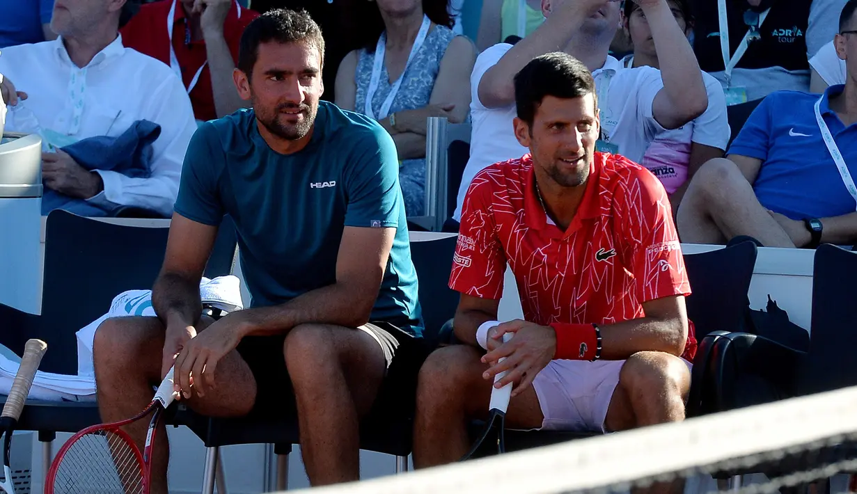 Petenis Serbia , Novak Djokovic duduk di sebelah Marin Cilic dari Kroasia selama pertandingan di sebuah turnamen di Zadar, Kroasia (19/6/2020). Novak Djokovic dan istrinya menderita COVID-19.  (AP Photo/Zvonko Kucelin)