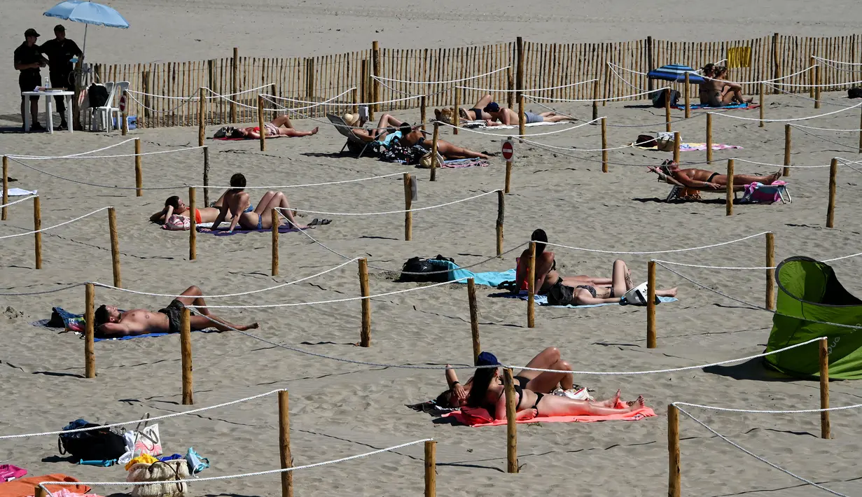 Orang-orang berjemur menikmati matahari di Sunset Beach dengan area terpisah untuk mematuhi jaga jarak di La Grande-Motte, Prancis, Selasa (26/5/2020). Ukuran area pemisah berupa kotak ini pun beragam yang dapat ditempati oleh dua, empat, atau enam orang. (Pascal GUYOT/AFP)