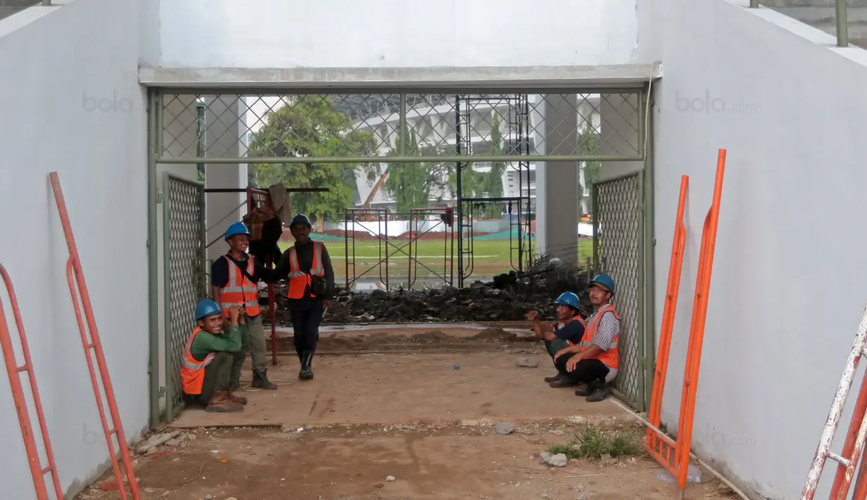 Pekerja berteduh saat hujan sebelum melanjutkan renovasi venue Atletik Stadion Madya di Kawasan Senayan Sport Center, Jakarta (12/10/2017). Renovasi tersebut menyambut Asian Games 2018. (Bola.com/Nicklas Hanoatubun)