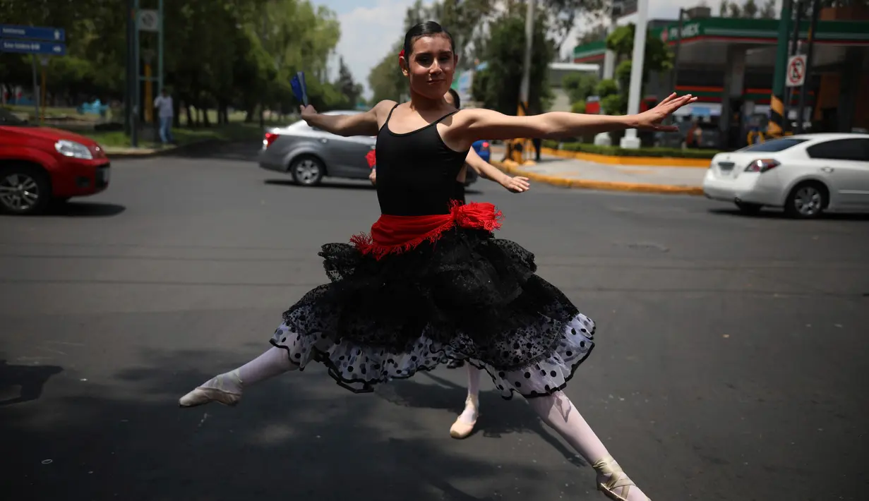 Balerina menampilkan tarian balet saat lampu merah di tengah jalanan Mexico City, 28 Juli 2018. Sejak pertunjukkan dimulai dua minggu lalu, para penari telah menarik perhatian fotografer, videografer, dan bahkan operator drone. (AP/Emilio Espejel)