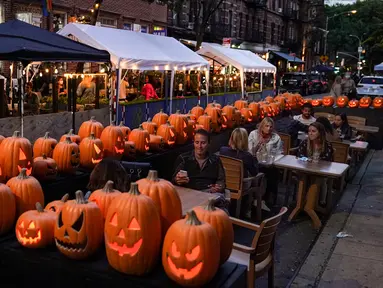 Pengunjung duduk di luar restoran yang menawarkan layanan area luar ruangan (outdoor) di New York pada 3 Oktober 2020. Kota itu mengizinkan restoran membuat area makan outdoor hingga ke trotoar dan jalanan sebagai upaya mengatasi dampak ekonomi COVID-19 yang berkelanjutan. (AP Photo/John Minchillo)