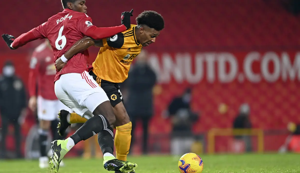 Gelandang Manchester United, Paul Pogba berusaha merebut bola penyerang Wolverhampton Wanderers, Adama Traore pada pertandingan lanjutan Liga Inggris di Stadion Old Trafford, Rabu (30/12/2020). MU kini tertinggal dua poin dari Liverpool yang berada di peringkat pertama. (Laurence Griffiths, Pool via