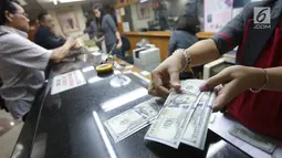 Teller menghitung mata uang dolar di Jakarta, Jumat (2/2). Deputi Gubernur BI Senior Mirza Adityaswara mengatakan, bahkan sebelum fluktuasi yang terjadi beberapa hari ini, rupiah sudah undervalue. (Liputan6.com/Angga Yuniar)