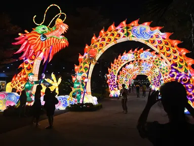 Pengunjung melihat lentera naga selama pratinjau media untuk Mid-Autumn Festival di Gardens by the Bay, Singapura, Selasa (27/8/2019). Festival ini sebagai penanda berakhirnya panen musim gugur, atau Mid-Autumn sekaligus merupakan momen untuk memanjatkan syukur kepada dewa-dewi. (Roslan RAHMAN/AFP)