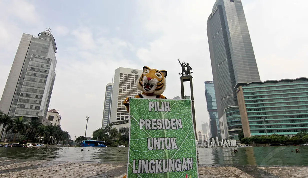 Aktivis Greenpeace membentangkan spanduk bertuliskan “Pilih Presiden Untuk Lingkungan” di Bundaran HI, Minggu (11/5/14). (Liputan6.com/Faizal Fanani)