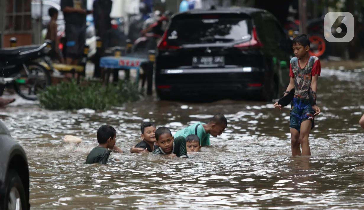 Anak anak bermain air di sebagian Jalan Bungur Besar Raya yang tergenang, Jakarta, Selasa (18/1/2022). Genangan air di sebagian Jalan Bungur Besar Raya dimanfaatkan anak-anak untuk bermain meski berbahaya. (Liputan6.com/Helmi Fithriansyah)