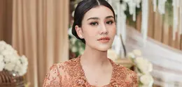Tampil dalam balutan kebaya brokat cokelat, ia memancarkan aura keibuan yang tenang dengan sentuhan makeup bernuansa peach yang lembut dan elegan. [@aaliyah.massaid].