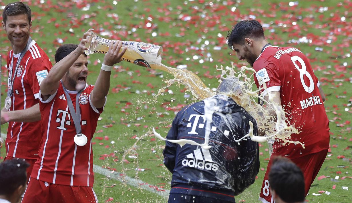 Pelatih Bayern, Carlo Ancelotti menerima seiraman bir oleh Juan Bernat saat perayaan gelar juara Bundesliga 2016-2017 di  Allianz Arena stadium, Munich, (20/5/2017).  (AP/Matthias Schrader)