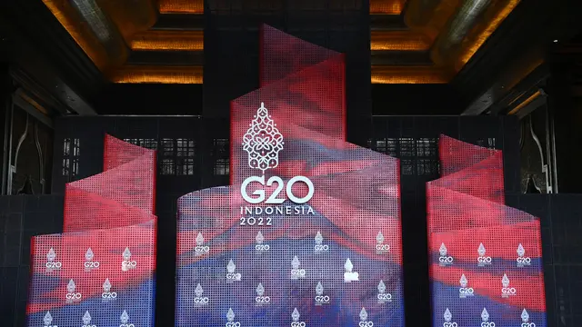 Backdrop bertuliskan G20 Indonesia 2022 lengkap dengan ikon gunungan bermotif batik. Warna backdrop didominasi warna merah dan biru. Tiga backdrop tersebut berbentuk lidah api.