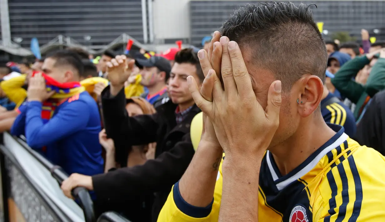 Suporter timnas Kolombia menutupi wajah dengan tangan saat timnya kalah dari Inggris pada siaran langsung pertandingan 16 besar Piala Dunia 2018 di Bogota, Selasa (3/7). Kolombia menyerah 3-4 dari Inggris melalui drama adu penalti. (AP/Fernando Vergara)
