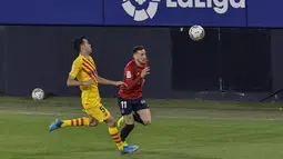 Penyerang Osasuna, Kike Barja membawa bola dari kejaran gelandang Barcelona, Sergio Busquets pada pertandingan lanjutan La Liga Spanyol di stadion El Sadar di Pamplona, Minggu (7/3/2021). Barcelona sukses menjaga jarak dua poin dengan pemuncak klsemen Atletico Madrid. (AP Photo/Alvaro Barrientos)