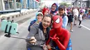 Ibu-ibu berswafoto dengan seorang yang kenakan kostum Spiderman pada acara amal di  CFD Jalan MH Thamrin, Jakarta, Minggu (6/8). Kegiatan tersebut untuk membantu anak-anak Panti Asuhan Muslimin Jaya. (Liputan6.com/Fery Pradolo)