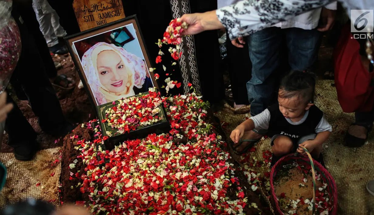 Cucu aktris senior Titi Qadarsih menaburkan bunga di pusara sang nenek saat pemakaman di TPU Tanah Kusir, Jakarta, Selasa (23/10). Sempat dirawat di Rumah Sakit Fatmawati, Titi Qadarsih meninggal saat dalam perjalanan pulang. (Liputan6.com/FaizalFanani)