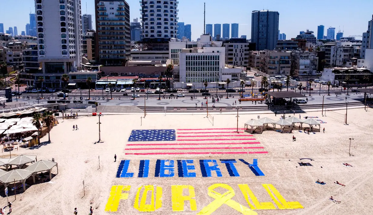 Foto udara yang diambil pada Jumat 4 Juli 2025 menunjukkan instalasi pasir yang menggambarkan bendera Amerika Serikat (AS) dan slogan “Liberty for All” atau Kebebasan untuk Semua di salah satu pantai di luar kantor cabang Kedutaan Besar (Kedubes) Amerika Serikat (AS) di Tel Aviv, Israel. (Jack GUEZ/AFP)