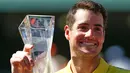 Petenis AS, John Isner memegang trofi Miami Terbuka 2018 usai mengalahkan petenis Jerman Alexander Zverev, Minggu (1/4). Isner menjadi petenis tertua yang memenangkan gelar turnamen Masters 1000 untuk kali pertama. (Michael Reaves/GETTY IMAGES/AFP)