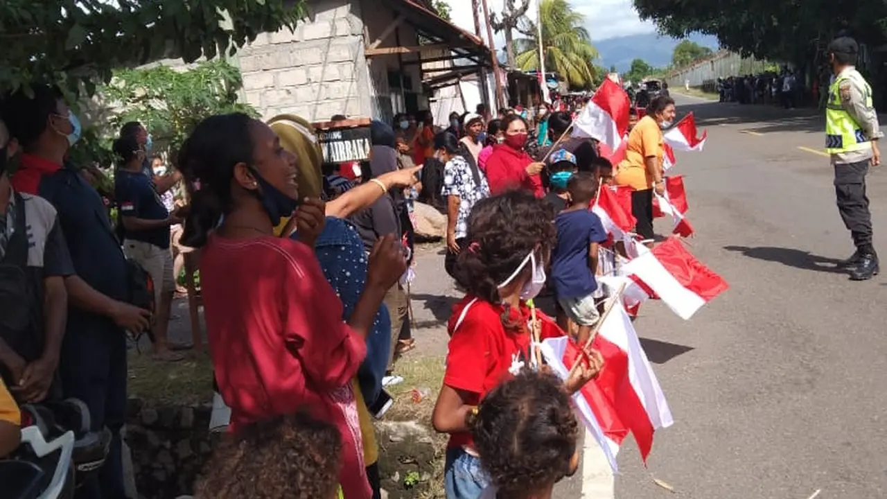 Memegang bendera mera putih, warga Kabupaten Sikka antusias menunggu kedatangan Presiden Joko Widodo. (Liputan6.com/Dionisius Wilibardus)
