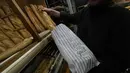 Pemilik toko roti Florence Poirier memasukkan baguette ke dalam kantong untuk pelanggan di toko roti, di Versailles, sebelah barat Paris, Selasa, 29 November 2022.  Baguette Prancis resmi diberi status warisan budaya takbenda UNESCO pada Rabu, 30 November 2022. (AP Photo/Michel Euler)