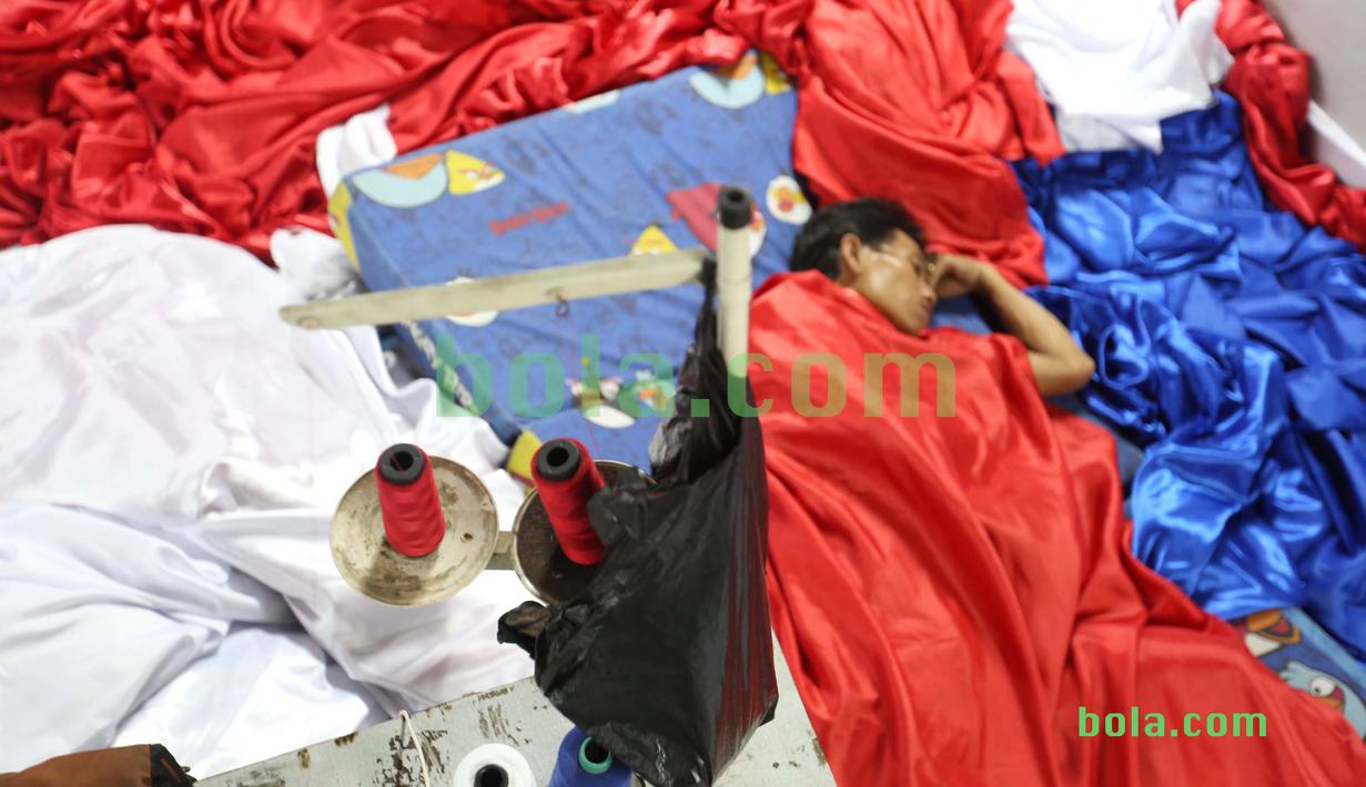 Suporter tertidur usai ikut dalam kegiatan menjahit bendera Merah-Putih raksasa di Tangerang, Sabtu (31/10/2015). Selain ingin mencatat rekor dunia, tema dasar adalah "One Soul, One Nation Untuk Sepakbola Indonesia".  (Bola.com / Nicklas Hanoatubun)