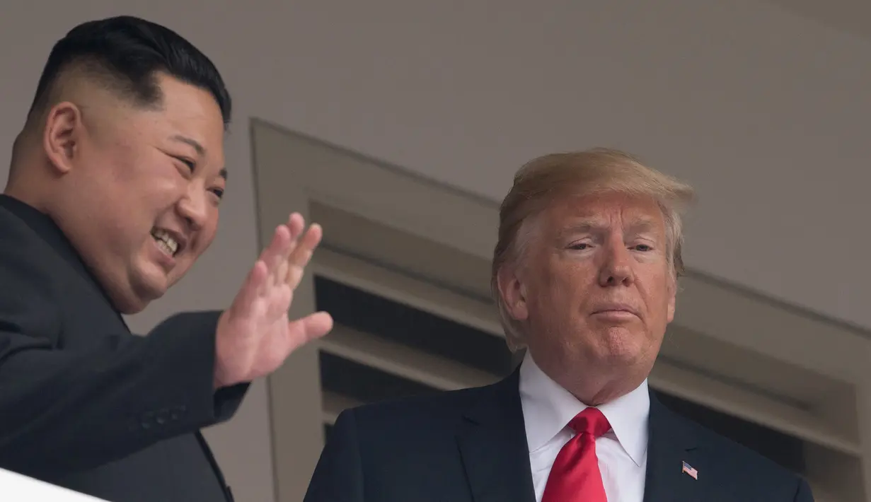 Pemimpin Korea Utara Kim Jong-un (kiri) melambaikan tangan saat tampil bersama Presiden AS Donald Trump di balkon Hotel Capella, Pulau Sentosa, Singapura, Selasa (12/6). Pertemuan keduanya membicarakan masalah denuklirisasi Korea Utara. (SAUL LOEB/AFP)