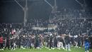 Suporter berlarian di lapangan pada babak pertama pertandingan 64 besar Piala Prancis antara Paris FC dan Olympique Lyon di stadion Charlety, Paris, Jumat (17/12/2021). Setelah 45 menit, penyiar stadion datang ke lapangan untuk meminta penggemar meninggalkan arena. (Bertrand GUAY/AFP)