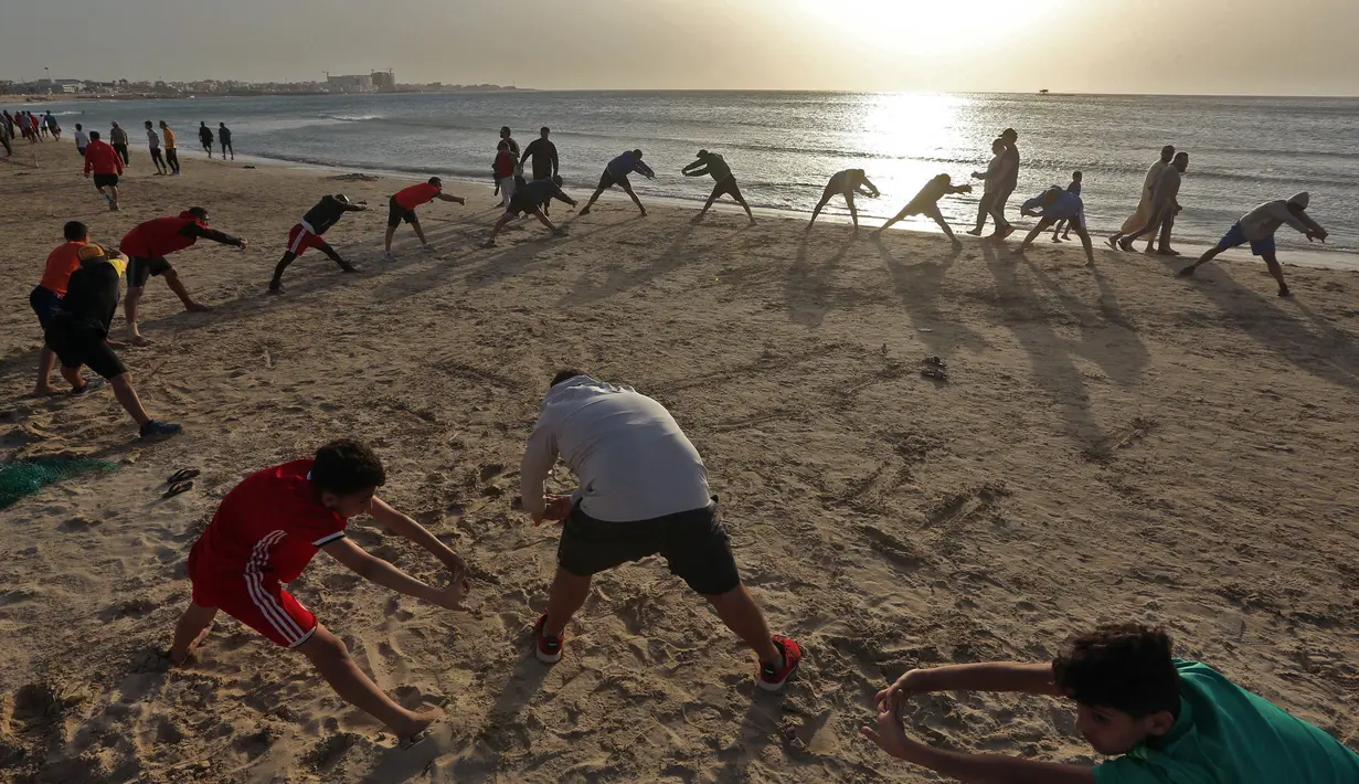Orang-orang berolahraga di pantai sembari menunggu waktu berbuka puasa selama bulan suci Ramadan, meskipun lockdown karena pandemi COVID-19, di ibu kota Tripoli, Libya pada Jumat (8/5/2020). (Photo by Mahmud TURKIA / AFP)
