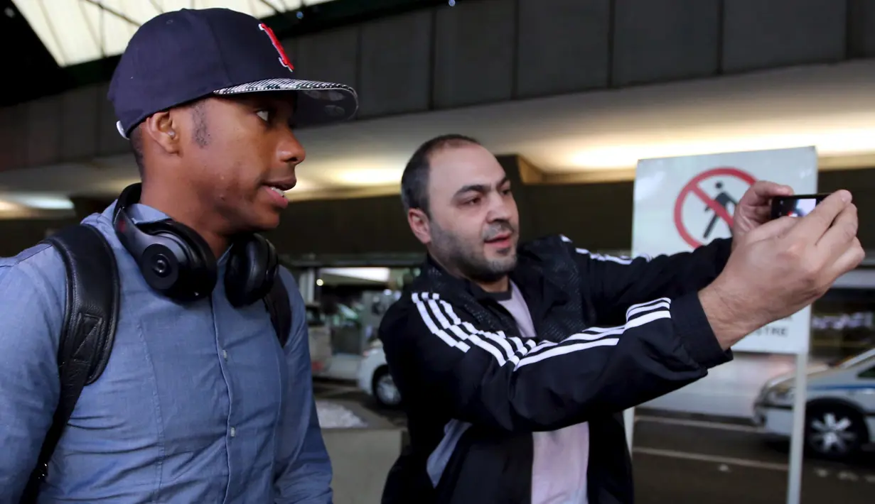 Seorang pria berselfie dengan penyerang Brasil, Robinho (kiri) di bandara Guarulhos International, Sao Paulo, Brasil, (28/6/2015). Brasil Kalah di perempat final melawan Paraguay dalam adu Penalti. (REUTERS/Paulo Whitaker)