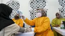 Seorang petugas kesehatan mengukur suhu tubuh seorang wanita sebelum memberinya vaksin virus corona COVID-19 Sinovac saat pelaksanaan vaksinasi di Masjid Raya Baiturrahman, Banda Aceh, Aceh, Selasa (7/9/2021). (CHAIDEER MAHYUDDIN/AFP)