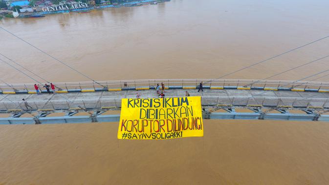 Sejumlah massa dari Fraksi Rakyat Indonesia (FRI) Jambi membentangkan spanduk aksi memperingati setahun UU Cipta Kerja di sungai Batanghari, Jambi, Selasa (5/10/2021). Mereka mengampanyekan penolakaran terhadap kerusakan lingkungan yang dilakukan oligarki