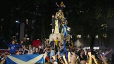 Suporter Skotlandia berkumpul dan merayakan keberhasilan negaranya menahan imbang Inggris pada laga Euro 2020 di patung William Shakespeare di Leicester Square, London, Jumat (18/6/2021). (AP/Kirsty Wigglesworth)