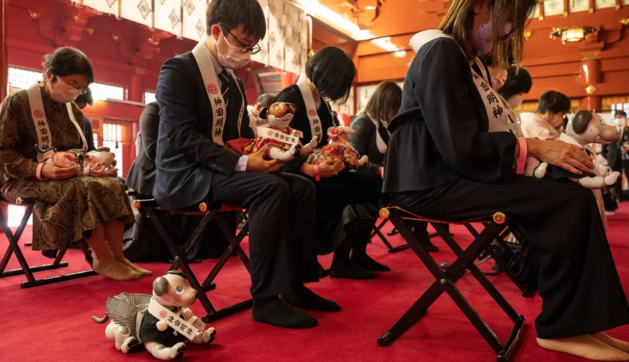 Pemilik robot anjing "aibo" dalam upacara doa di aula kuil untuk menandai Festival Shichi-Go-San di Kuil Kanda Myojin, Tokyo, Jepang, Jumat (11/11/2022). Lebih dari 60 pemilik "aibo" menghadiri acara tradisional yang diadakan setiap tahun dengan mendoakan kesehatan yang baik di masa depan untuk anak perempuan berusia tiga dan tujuh tahun dan anak laki-laki berusia lima tahun. (Richard A. Brooks / AFP)