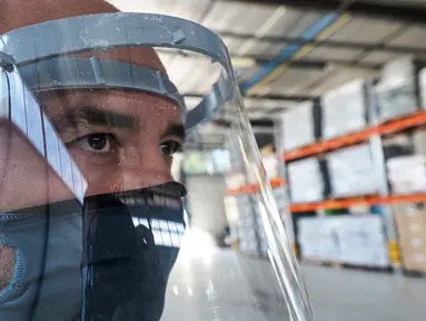 Pekerja memakai pelindung wajah yang terbuat dari kombinasi plastik dan tekstil di perusahaan Plaxtil, Chatellerault, Prancis, 25 Agustus 2020. Startup di Prancis, Plaxtil, mendaur ulang masker dan plastik untuk dijadikan pelindung wajah, pembuka pintu, dan pengencang masker. (GUILLAUME SOUVANT/AFP)