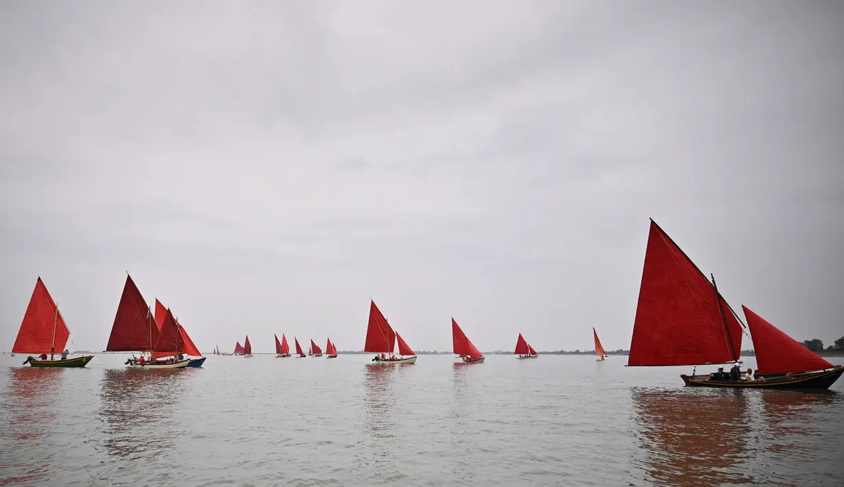 Anggota asosiasi pelayaran budaya berlayar dalam acara Regatta Merah di Venesia, Italia, Minggu (20/6/2021). Red Regatta mengumpulkan lebih dari 50 perahu tradisional Venesia dengan 52 layar warna merah. (MARCO BERTORELLO/AFP)