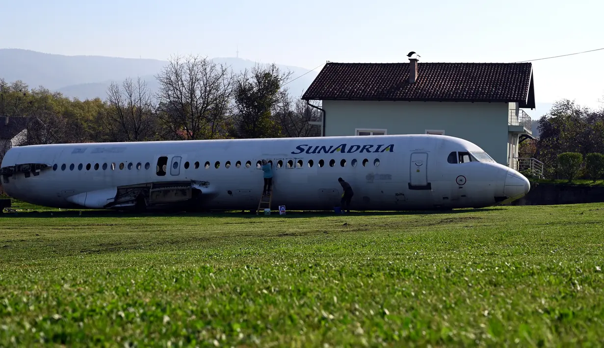 Dua wanita membersihkan badan pesawat Fokker-100 di halaman rumah warga setempat di Strmec Stubicki, Kroasia, 26 Oktober 2019. Pesawat yang membujur di kebun Robert Sedlar (50) itu merupakan buatan 1991 dan beroperasi melayani penerbangan komersial di Kroasia sampai 2014. (Denis LOVROVIC / AFP)