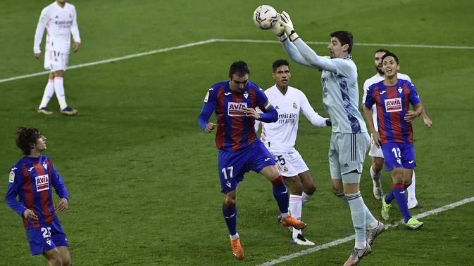 Penjaga gawang Real Madrid Thibaut Courtois, mengontrol bola di depan pemain Eibar Kike Garcia pada laga La Liga Spanyol di stadion Ipurua, di Eibar, Spanyol utara, Minggu, 20 Desember 2020. (Foto AP / Alvaro Barrientos)