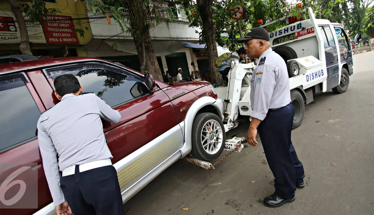 Petugas menderek kendaraan roda empat yang parkir sembarangan di kawasan Jatinegara, Jakarta Timur, Senin (28/12). Meski sudah ditertibkan, pengendara masih tak menghiraukan peraturan tersebut yang mengakibatkan kemacetan. (Liputan6.com/Immanuel Antonius)