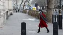 Seorang pejalan kaki yang mengenakan masker untuk mengurangi penyebaran Covid-19, berjalan di sepanjang Whitehall di pusat kota London (5/1/2022). Kasus Covid-19 harian negara itu menembus 200.000 untuk pertama kalinya. (AFP/Tolga Akmen)