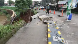 Pejalan kaki melintasi lokasi longsor di daerah bantaran sungai Ciliwung, Pengadegan Timur, Jakarta, Selasa (12/4/2022). Dampak longsor di kawasan tersebut menyebabkan sebagian ruas jalan harus ditutup untuk sementara waktu. (Liputan6.com/Herman Zakharia)
