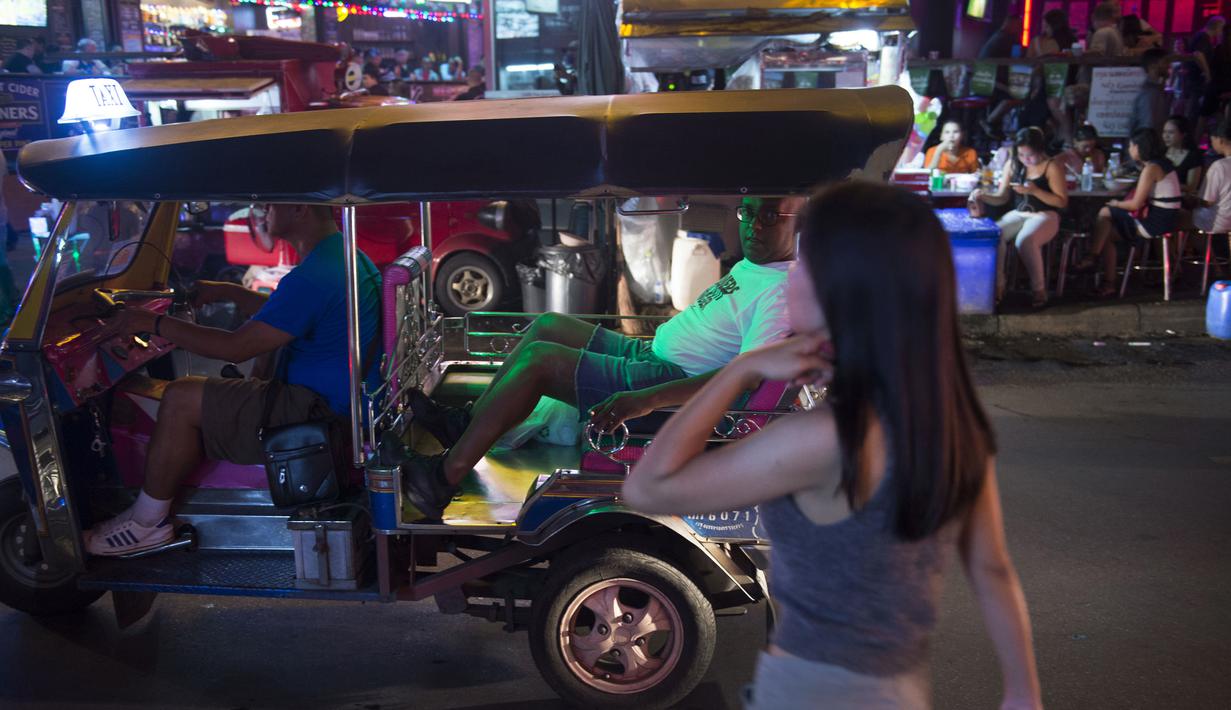 Foto pada 11 Oktober 2018 memperlihatkan turis asing menaiki tuk-tuk melintasi Nana Red Light Distrik di Bangkok, Thailand. Kawasan tersebut merupakan tempat lokalisasi hiburan malam paling tersohor di Bangkok. (Romeo GACAD / AFP)