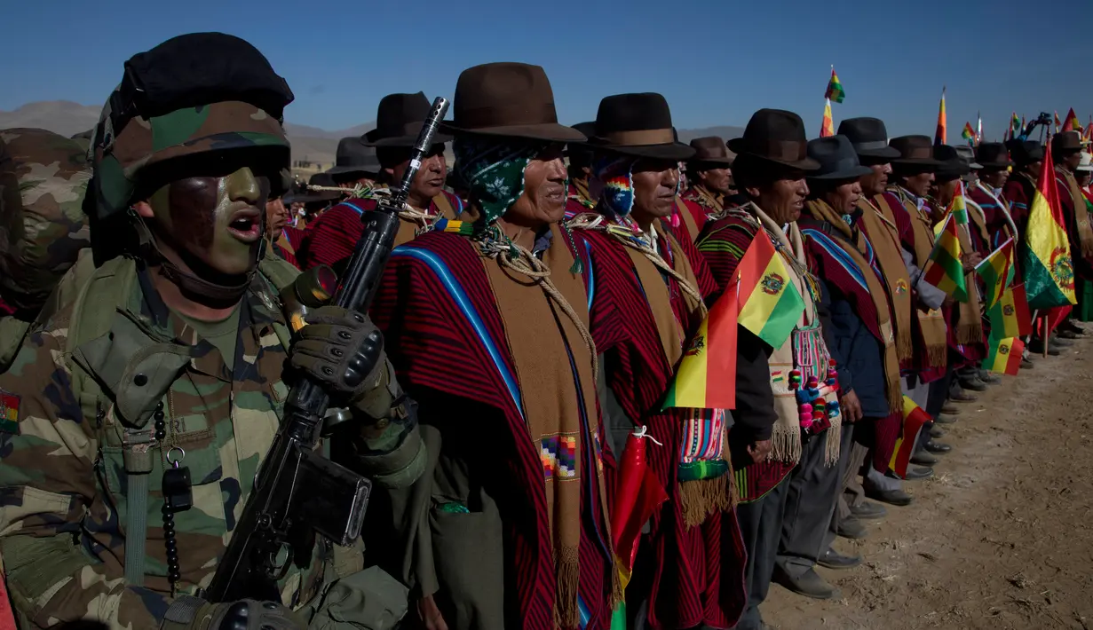 Tentara berbaris bersama pria Aymara menyanyikan lagu kebangsaan mereka saat pawai ulang tahun tentara Bolivia ke-192 di Kjasina, Bolivia (7/8). Hal ini unik dari upacara militer ini adalah karena digelar di tengah gurun. (AP Photo/Juan Karita)