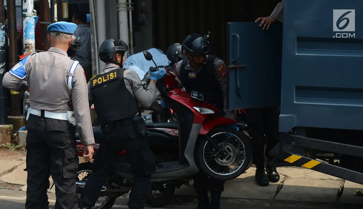 Polisi membawa sepeda motor saat menggelar olah TKP di rumah terduga teroris di Nanggewer, Cibinong, Bogor, Jawa Barat, Sabtu (18/5/2019). Dari lokasi penggerebekan, polisi menyita barang bukti berupa pistol jenis FN dan bahan baku serta bahan jadi peledak. (merdeka.com/Imam Buhori)