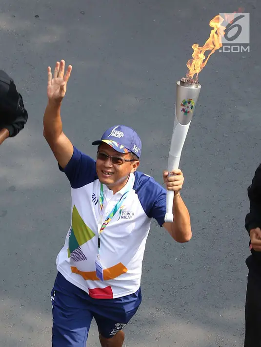 Pelari membawa obor Asian Games 2018 dalam Torch Relay Asian Games 2018 di kawasan TMII, Jakarta Timur, Rabu (15/8). Kota Jakarta menjadi persinggahan terakhir api Asian Games yang dimulai dari wilayah Jaktim dan Jaksel. (Liputan6.com/Immanuel Antonius)