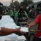 Warga menerima pembagian nasi bungkus gratis di Posko Perjuangan Rakyat (POSPERA), Jakarta, Rabu (10/3/2021). Pembagian 500 nasi bungkus beserta masker dan vitamin secara gratis setiap harinya dalam bentuk meringankan beban warga di tengah pandemi Covid-19. (merdeka.com/Imam Buhori)