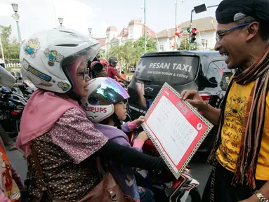 Komunitas Gerakan Literasi Aksara Jawa membagikan kalender berhuruf Jawa kepada  pengunjung  pada peringatan Hari Aksara Internasional ke-50 di Titik Nol km, Yogyakarta, Kamis (8/9). (Liputan6.com/ Boy Harjanto)