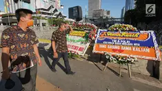 Pekerja melintas di dekat karangan bunga yang bertuliskan ucapan apresiasi bagi TNI dan Polri di samping gedung Bawaslu, Jakarta, Jumat (24/5/2019). Karangan bunga itu sebagai wujud apresiasi bagi TNI dan Polri dalam menjaga ketertiban dan keamanan saat aksi 22 Mei. (Liputan6.com/Herman Zakharia)