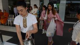 Para pekerja wanita mengenakan kostum tradisional mempersiapkan persembahan bagi para biksu Budha selama upacara keagamaan sebagai persiapan festival tahun baru Songkran di luar kantor di Bangkok, Thailand (9/4). (AFP Photo/Romeo Gacad)