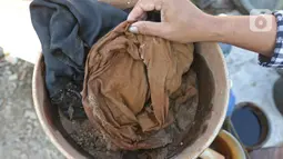 Warga menunjukkan media penyaringan air yang terdiri dari kain dan pasir di Desa Sukaringin, Sukawangi, Kabupaten Bekasi, Jawa Barat, Jumat (10/9/2021). Menurut warga, saat musim kemarau kualitas air tanah berwarna hitam dan sudah berlangsung selama delapan bulan. (Liputan6.com/Herman Zakharia)