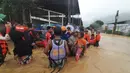 Penduduk sedang mengarungi banjir yang disebabkan oleh Topan Rai saat mereka dievakuasi ke tempat yang lebih tinggi di Kota Cagayan de Oro, Filipina selatan, Kamis (16/12/2021). (Philippine Coast Guard via AP)